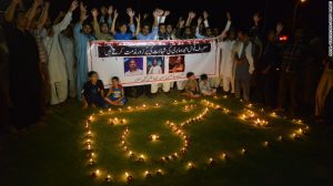 Pakistani Shiite Muslims shout slogans next to oil lamps to pay tribute to Sufi musician Amjad Sabri.